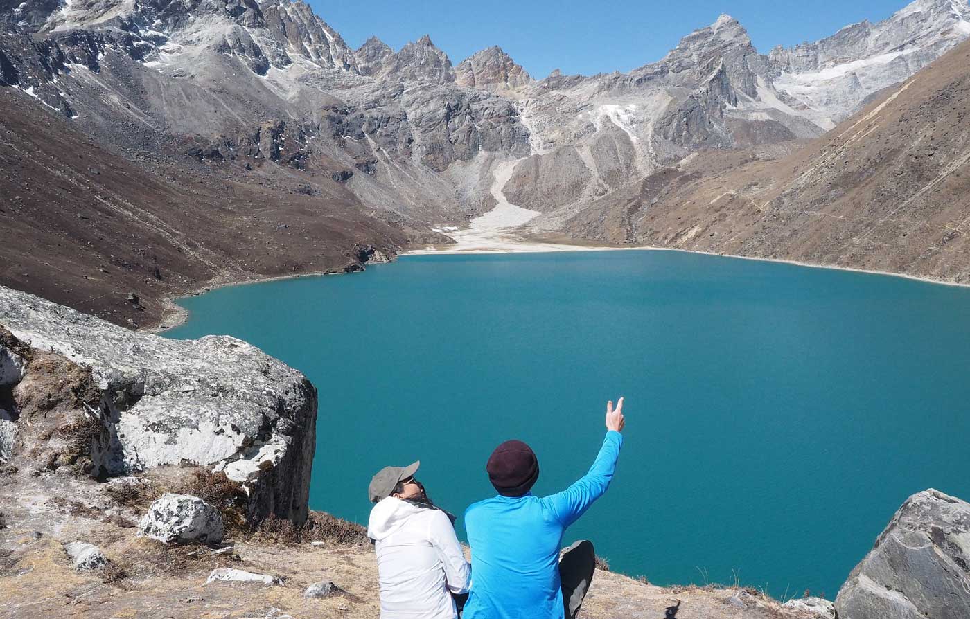 two travelers watching Gokyo Lake in clear weather.